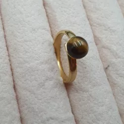 la bague gentiane, ajustable et ornée d'une pierre naturelle oeil de tigre, est en acier inoxydable doré.