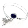 Le bracelet jonc Sylvaine est en acier inoxydable argenté, réglable, avec un cabochon en lapis-lazuli et une breloque.