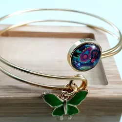 Le bracelet jonc Sylvaine est en acier inoxydable doré, réglable, avec un cabochon en verre , et une breloque verte.