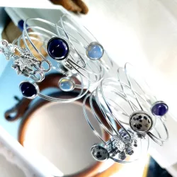 Le bracelet jonc Sylvaine est en acier inoxydable argenté, avec un cabochon en verre ou pierre naturelle et une breloque.