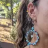 Boucles d’oreilles Setaria portées par une jeune femme, bijou pendante artisanal en acier inoxydable