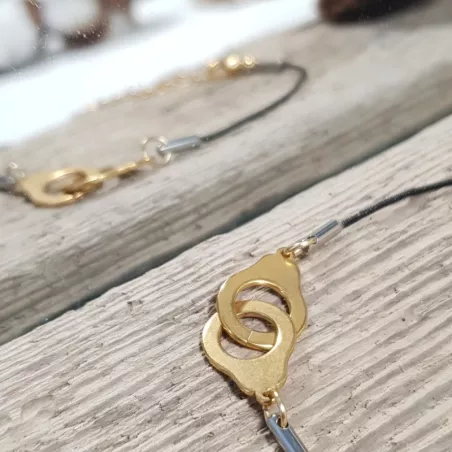 le bracelet "Patoche" en fil de cuir noir et menotte,  en acier inoxydable doré