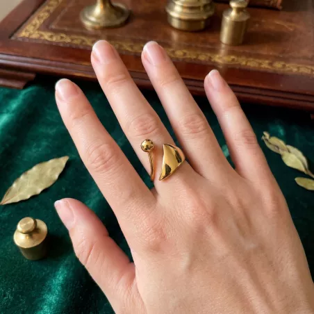 Bague Spira dorée portée à la main, acier inoxydable poli sur velours vert